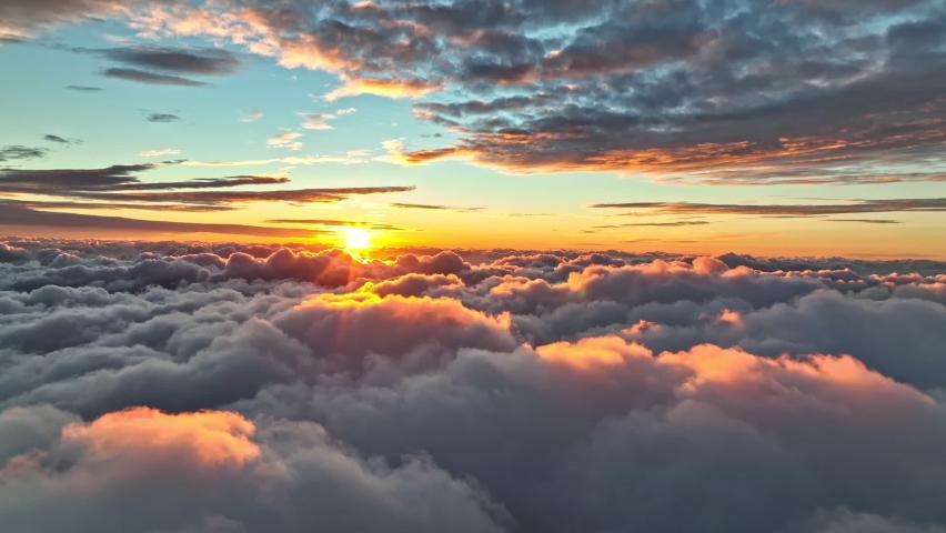 Magnificent sunrise on dense clouds. Aerial view of sun rises from behind the clouds starting a new day. Rising sun illuminates clouds in bright pink color. Great sunrise at Madeira island