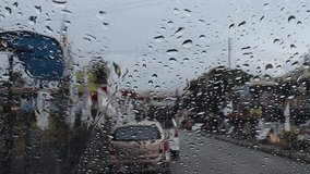 A video of the slowing down of the weather is raining and dripping on the windscreen of a car against the backdrop of the Ranau district town decorated by political flags in Sabah,Malaysia.