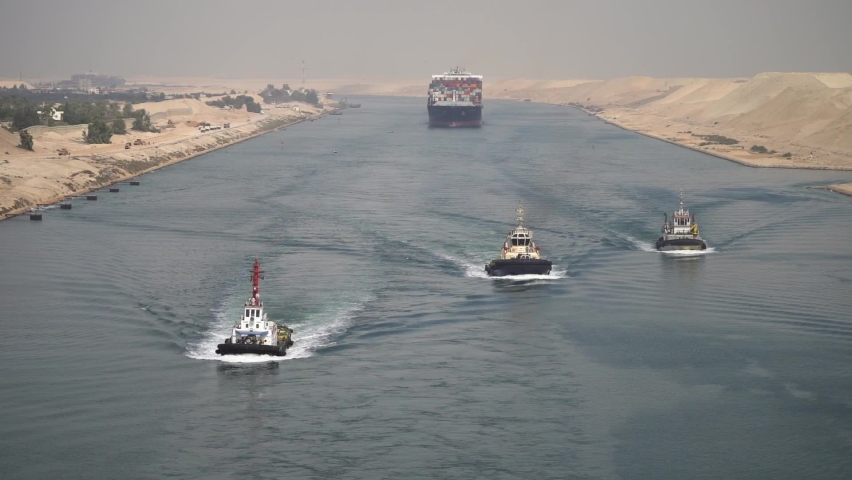Huge cargo ships with pilot boats navigate by Suez Canal, Egypt. Concept of transportation and logistics  Royalty-Free Stock Footage #1096760285