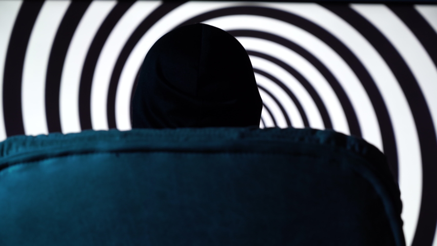 Back view of man sitting on chair with hypnotic black spiral