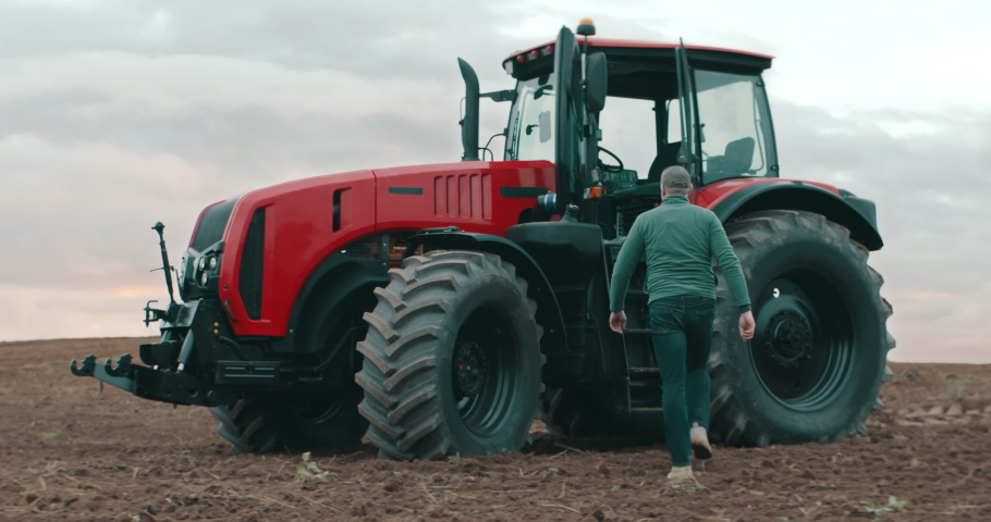 Hero shot portrait of 50s farmer walking towards tractor early in the morning in the field. Shot with 2x anamorphic lens Royalty-Free Stock Footage #1096761651