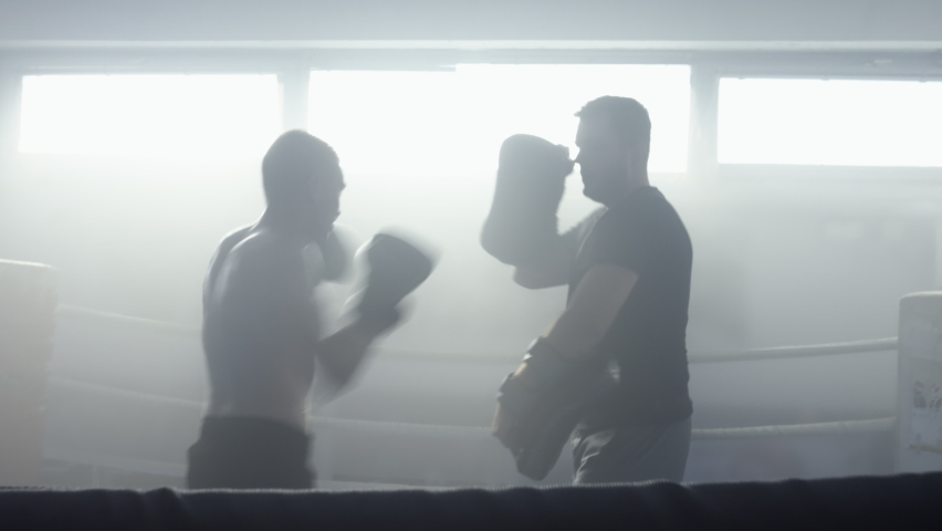 Kickboxing coach and fighter training leg strike in fighting ring zoom in shot, teaching attack punch technique. Fighting instructor and kickboxer practicing
