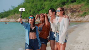 Groups of multi-ethnic teenage girls talking online by video call on cellphone in summer sea on the beach. Portrait of smiling woman having conversation by video chat outside.