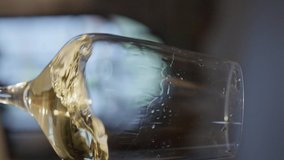 Waving gold white wine in a glass on defocused dark background . Beautiful stock footage for wine commercial . Close up video of wine mixing process inside goblet . Slow Motion . Vertical view.
