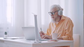 Man in his 60s working as online tutor, having video call, talking to coworkers