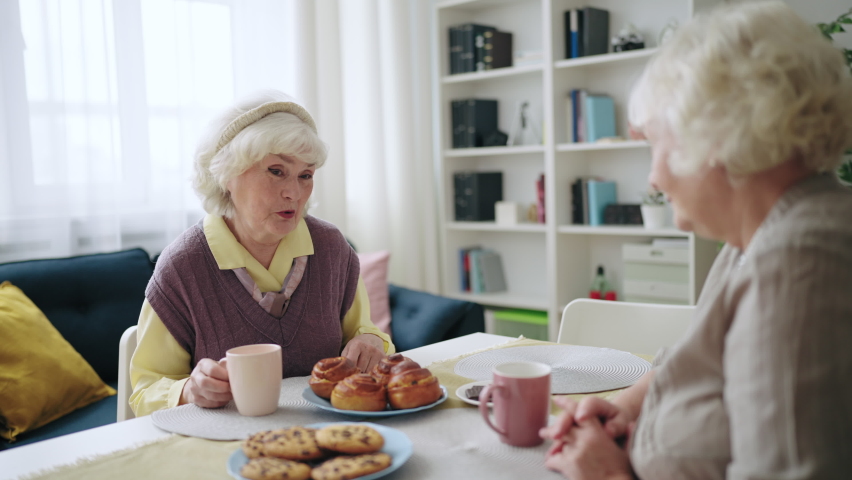 Two women in their 60s gossiping at home, friends meeting for afternoon tea | Shutterstock HD Video #1096775193