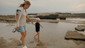 Relaxed family going beach resort seaside coast enjoy summer travel vacation slow motion mother and son kid walking shore holding hands with love spending time together at tropical seascape scenery - Powered by Shutterstock - Get 15% off with code: PIKWIZARD15