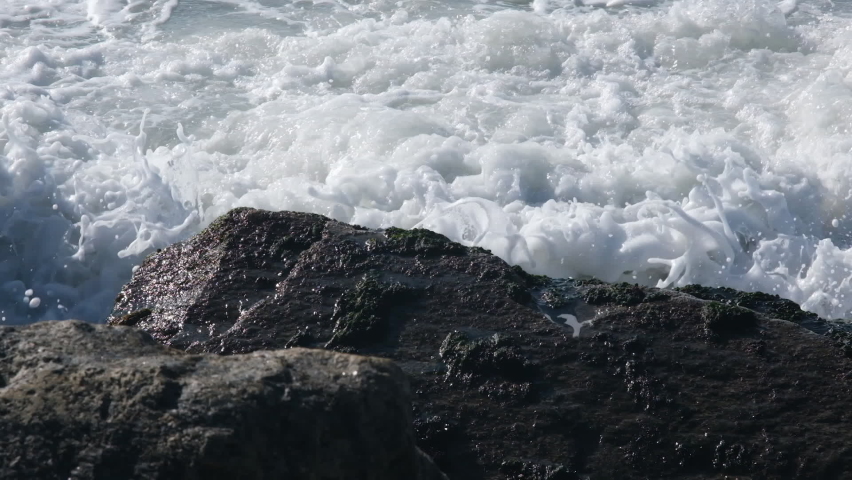 Ocean waves crash against the rocks on the coast. Full HD slow-motion view on beautiful Atlantic ocean waves with foam and stone beach. High-quality FullHD footage. Royalty-Free Stock Footage #1096779125