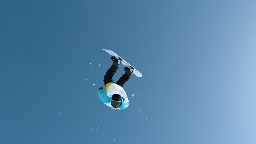 SLOW MOTION: Male tourist snowboarding in Slovenia does a spectacular backflip. Unrecognizable snowboarder jumps off a kicker and does an acrobatic flip trick. Shot of a snowboarder doing tricks.