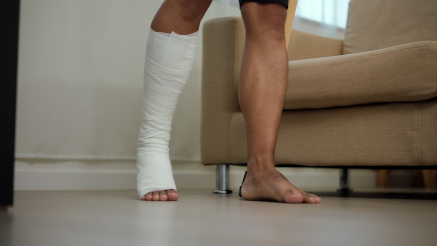 Man suffered pain from accident fracture broken bone injury with leg splints in cast, neck splints collar, sling support arm walking at home with crutch. Social security and health insurance concept. Royalty-Free Stock Footage #1096786145