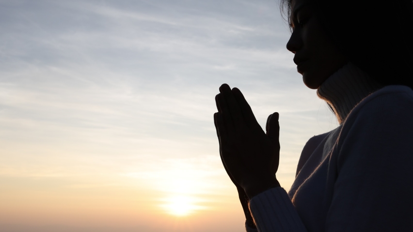 Silhouette of a women is praying to God on the mountain. Praying hands with faith in religion and belief in God on blessing background. Power of hope or love and devotion.  Royalty-Free Stock Footage #1096790421