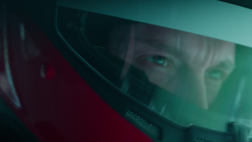 ECU Portrait of sports car driver in protective helmet racing on a speedway. Fast speed, motorsport. Daytime shot