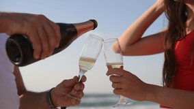 Cheers! man hand pour Bubble drink to glass. two people cheering with champagne Christmas on vacation on summer beach in the background blue sky and sea  - Powered by Shutterstock - Get 15% off with code: PIKWIZARD15