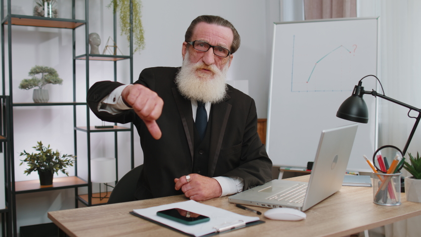 Dislike. Upset senior businessman working on laptop computer at home office thumbs down sign gesture, expressing discontent, disapproval, dissatisfied bad work. Displeased serious freelancer old man | Shutterstock HD Video #1096794777