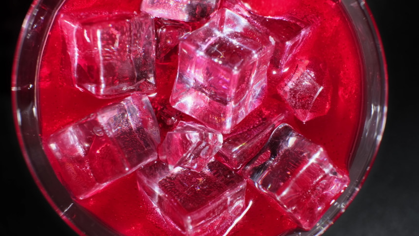 Red cocktail with ice cubes in glass on dark background close-up top view. - Powered by Shutterstock - Get 15% off with code: PIKWIZARD15