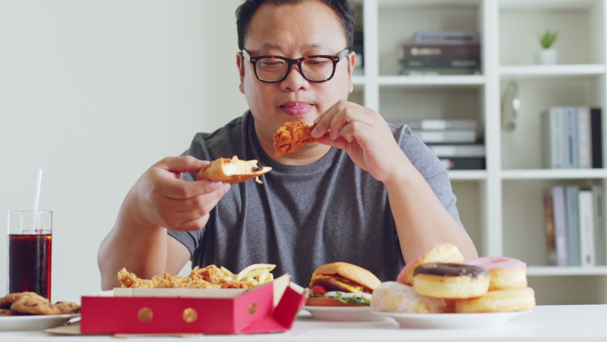 Fat asian man enjoy to eat junk food, hamburger, pizza, fried chicken | Shutterstock HD Video #1096799257