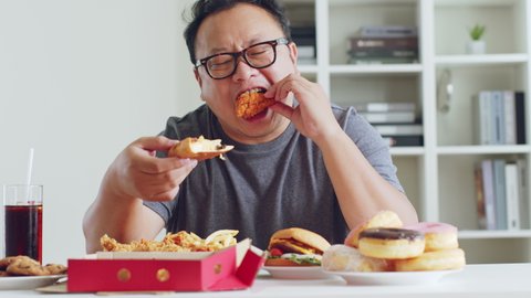 Fat asian man enjoy to eat junk food, hamburger, pizza, fried chicken: stockvideo