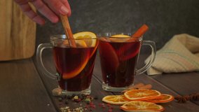 Mulled wine, woman's hand stirs red wine alcohol drink with cinnamon stick, Christmas punch with orange, apple fruit, spice, winter alcohol cocktail, slow 4k video - Powered by Shutterstock - Get 15% off with code: PIKWIZARD15