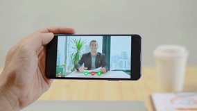 Working from home office, Caucasian businessman having Video call with colleagues on smart phone from office, using Video Conferencing technology, Close up man's hand holding smart phone