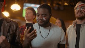 Portrait of an Excited Young Black Man Holding a Smartphone, Anxious About a Sports Bet on His Favorite Soccer Team. Lively Successful Emotions When Football Team Scores a Winning Goal. - Powered by Shutterstock - Get 15% off with code: PIKWIZARD15