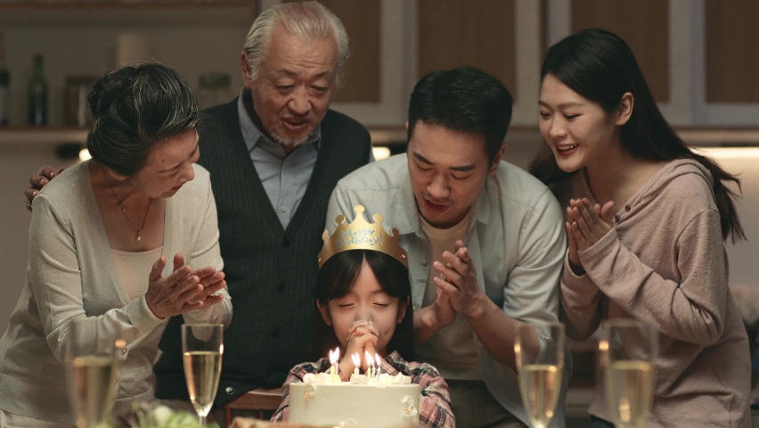 three generation asian family celebrating little girl's birthday at home