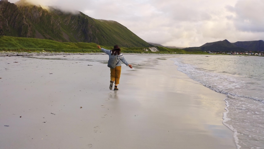 heerful girl runs with her hands up in joy. Village on Andoya Blake Island. Vesteralen Archipelago, Norway Royalty-Free Stock Footage #1096812095