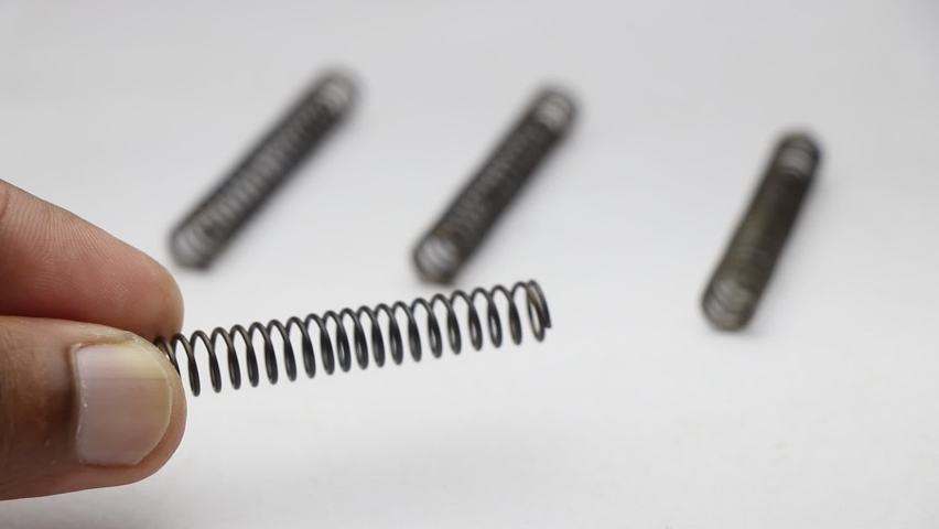 Small metal spring held in hand with other similar pieces on a white background Royalty-Free Stock Footage #1096813251
