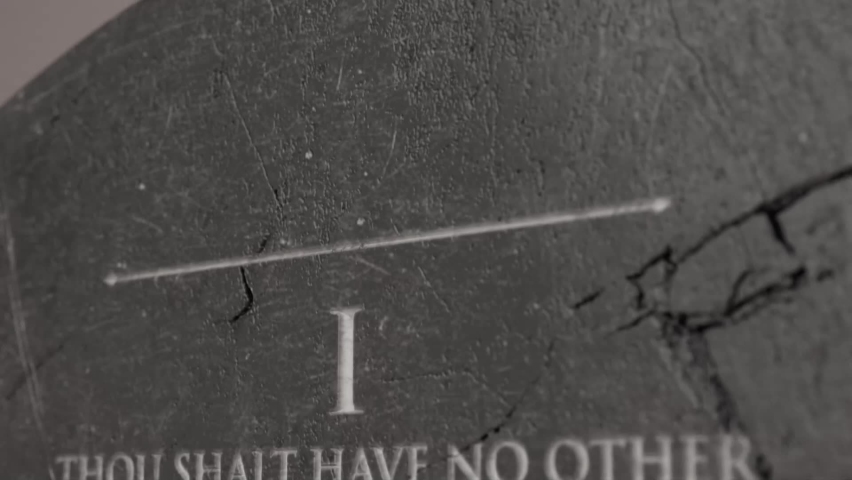 A slow close up pan across a stone tablet with the first five of the ten commandments inscribed onto them