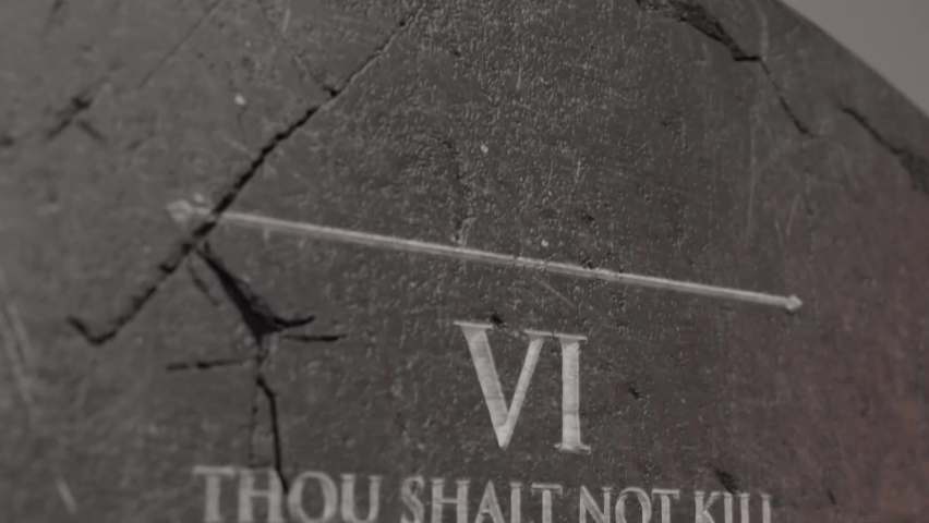 A slow close up pan across a stone tablet with the second five of the ten commandments inscribed onto them