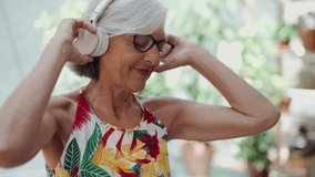 Video of cheerful senior woman listening to music and using her laptop while sitting in greenhouse. - Powered by Shutterstock - Get 15% off with code: PIKWIZARD15
