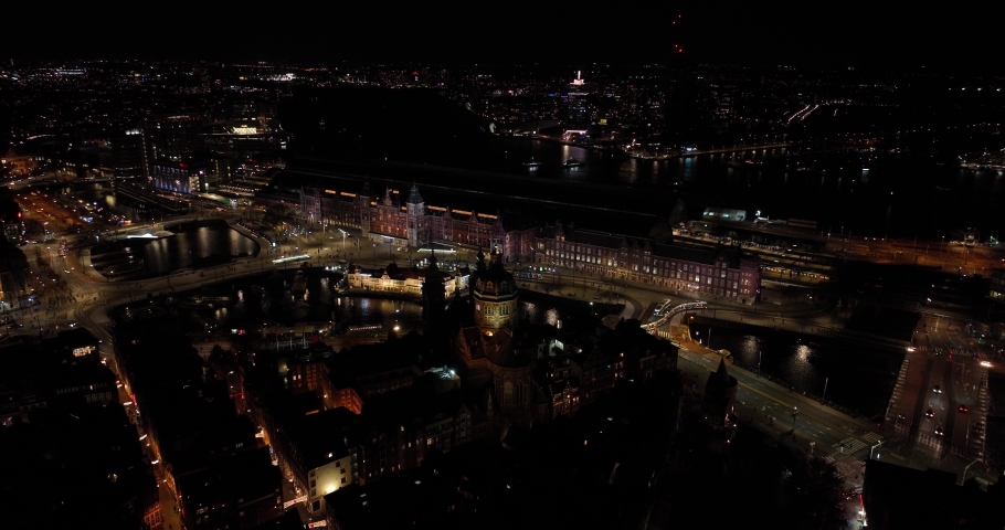 Amsterdam city center skyline by night aerial drone overhead view. Amsterdam Centraal, Ij, Oosterdok, Prins Hendrikkade, public transport, traffic at night. Bright lights urban