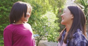Video of happy asian mother and daughter having fun in garden. Family, motherhood, relations and spending quality time together concept digitally generated video.