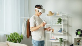 Korean man using virtual reality glasses with controllers, playing video games, Asian guy gamer wearing new generation gaming headset for entertainment at home, future technology concept.