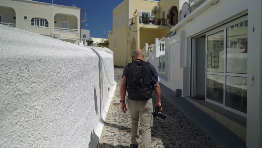Following a man walking down a narrow street in Santorini island