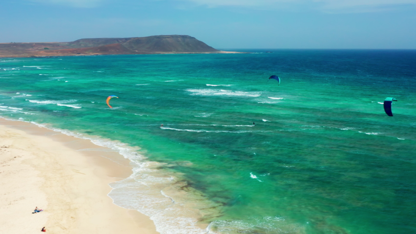 Flying over kiters in Sal, Cape Verde.
Drone bird eye view over professional Kite surfers training in Cape Verde. Turquoise wavy ocean. Bright Blue Sky.