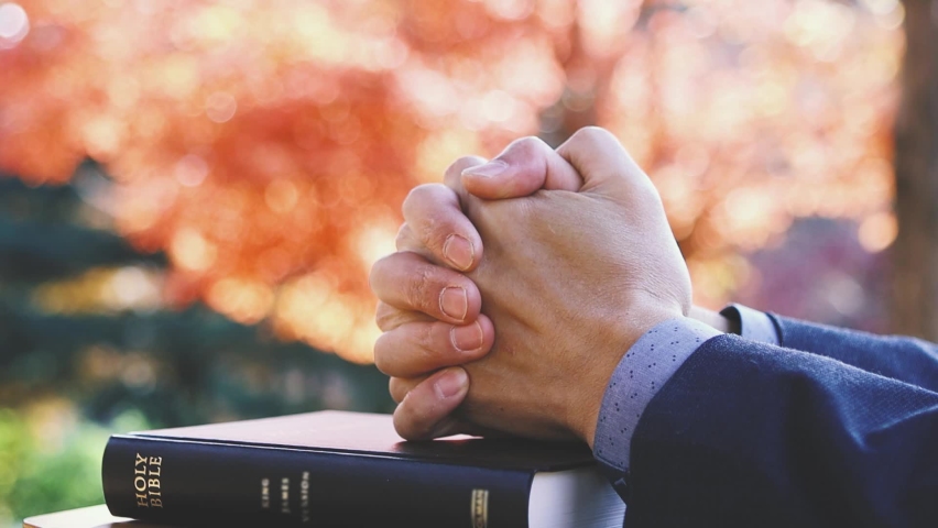 A Christian praying with his hands together on the Holy Bible on Thanksgiving Day and a beautiful autumn landscape with sunlight
 | Shutterstock HD Video #1096835729