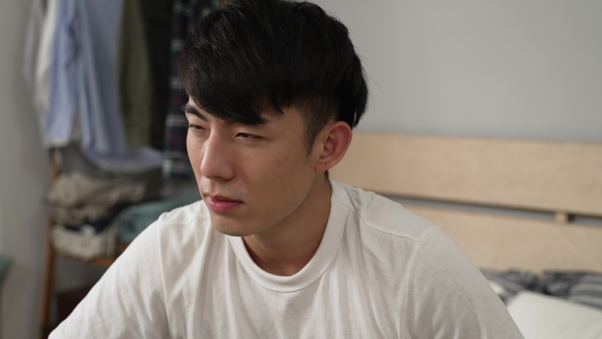 headshot of a dizzy asian male massaging himself with grimacing face while trying to ease pain in the head caused by hangover after rising in the morning at home Royalty-Free Stock Footage #1096836689