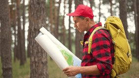 Tourist with map in forest park. Rest at nature. Hiking in forest park. Orientation on map in forest. Tourist travels on foot. Orientation on map for trip. Tourist rest in natural park - Powered by Shutterstock - Get 15% off with code: PIKWIZARD15