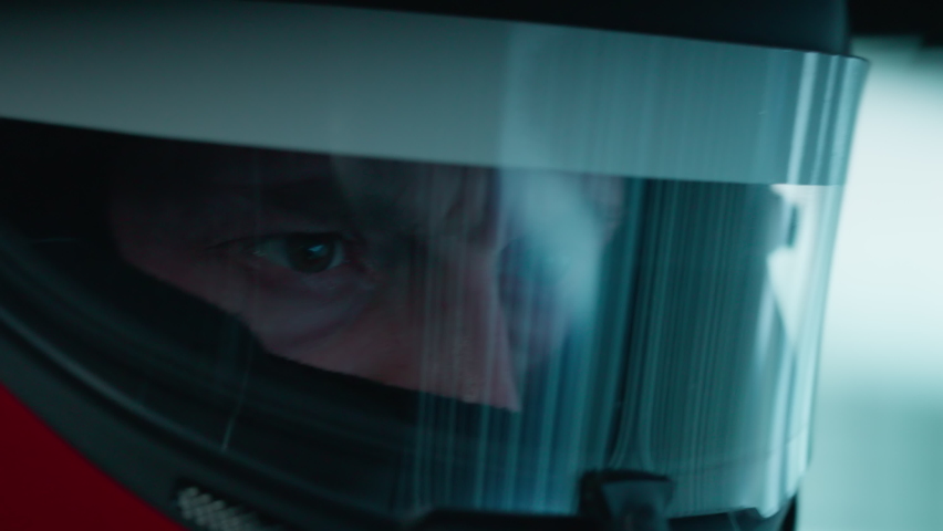 ECU Portrait of sports car driver in protective helmet racing on a speedway. Fast speed, motorsport. Daytime shot