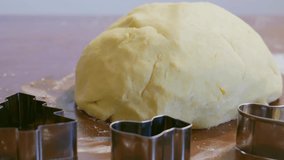 Shortbread dough ball with flour on wooden table, with cookie cutters. Slow motion video.