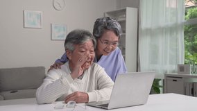 Happy old Asian senior grandparents couple waving hand making online video call enjoying family virtual meeting digital webcam videocall chat talking, looking at laptop computer at home.