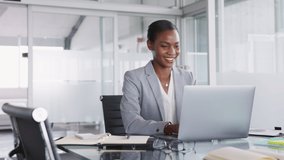 Mature african american businesswoman taking notes in notebook while using laptop at office. Mid adult black woman entrepreneur writing details on book while working on laptop in office. Video call. - Powered by Shutterstock - Get 15% off with code: PIKWIZARD15