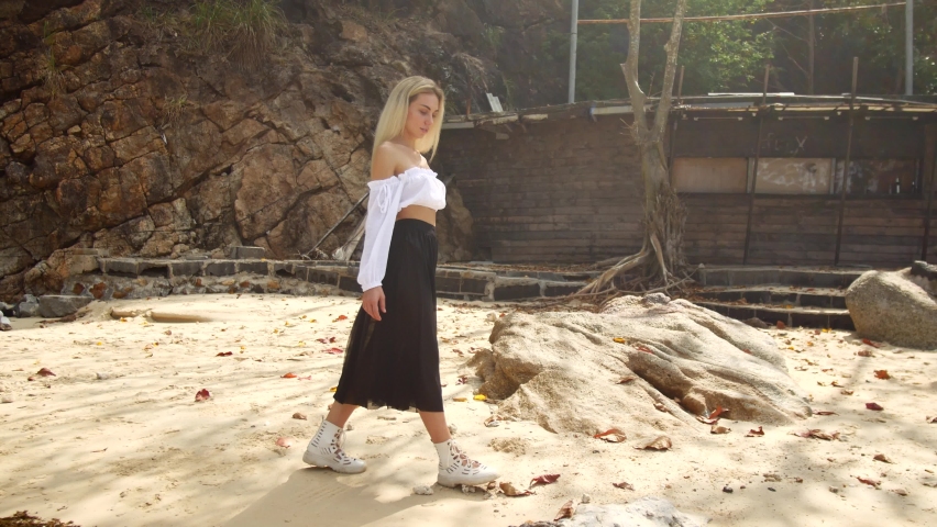 A young blonde walks along the sea. 