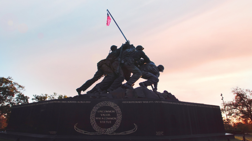 Marine Corps War Memorial – Cinematic 4K camera-stabilized footage of the iconic United States Marine Corps War Memorial, also known as the Iwo Jima Memorial, located in Arlington, Virginia, near Washington, DC. Impressive establishing shot featuring the monumental bronze sculpture depicting six U.S. Marines raising the American flag during the historic Battle of Iwo Jima in World War II. Inspired by one of the most famous photographs in American military history, this powerful national landmark honors the courage, sacrifice, and service of United States Marines who have died in defense of their country. Professionally captured ultra-high-definition footage showcasing the dramatic sculptural composition, historic symbolism, and patriotic significance of this celebrated military monument. Ideal for television news broadcasts, military documentaries, historical films, Veterans Day and Memorial Day programming, patriotic productions, educational content, and editorial storytelling. High-quality cinematic stock footage with smooth stabilized camera movement, suitable for broadcast television, streaming platforms, military history features, commemorative events, and productions exploring American patriotism, armed forces, national remembrance, World War II, and the legacy of the United States Marine Corps.