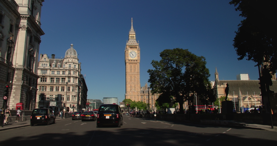 BIG BEN, LONDON, ENGLAND, UNITED KINGDOM – 22 JUNE 2022 Traffic and in Parliament Square in front of Big Ben, Houses of Parliament and road sign to Trafalgar Square and Lambeth Bridge, London, England