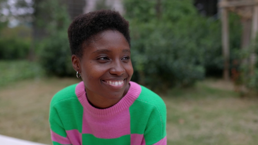 Smiling young african woman relaxing in public park sitting outdoors. High quality 4k footage