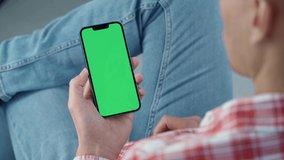 Man Using Smartphone in Vertical Mode with Green Mock-up Screen, Doing Swiping, Scrolling Gestures. Internet Social Networks Browsing News, Financial Reports In Phone