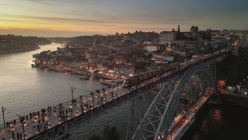Aerial view of Porto cityscape showing train crossing the Dom Luis I Bridge over the Douro River at dusk in Porto (Oporto), Portugal. Royalty-Free Stock Footage #1096860111