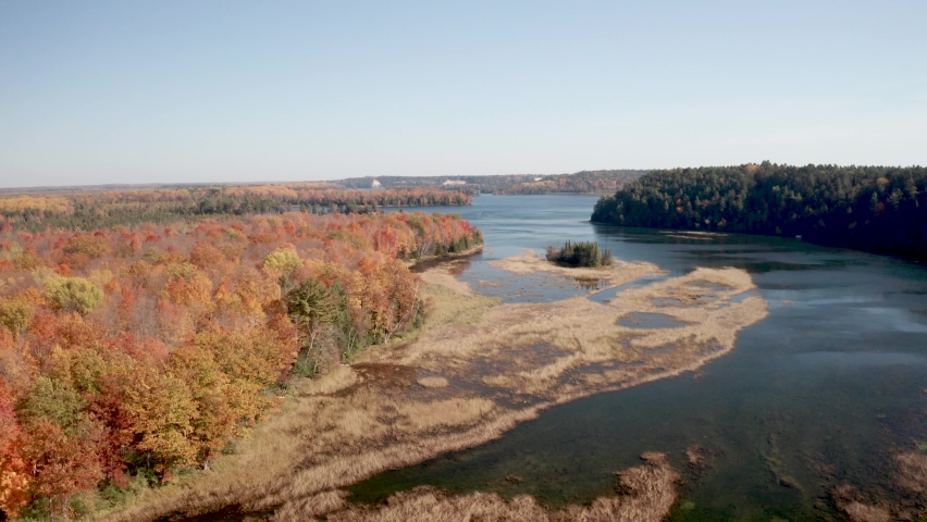 Au Sable River in Michigan during fall colors with drone video moving low and forward.