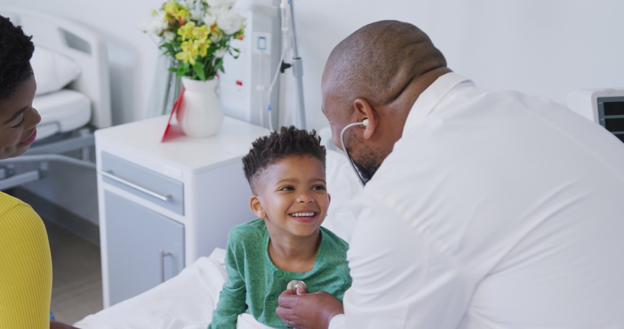African american male doctor examining child patient, using stethoscope at hospital. Medicine, healthcare, lifestyle and hospital concept. Royalty-Free Stock Footage #1096865129